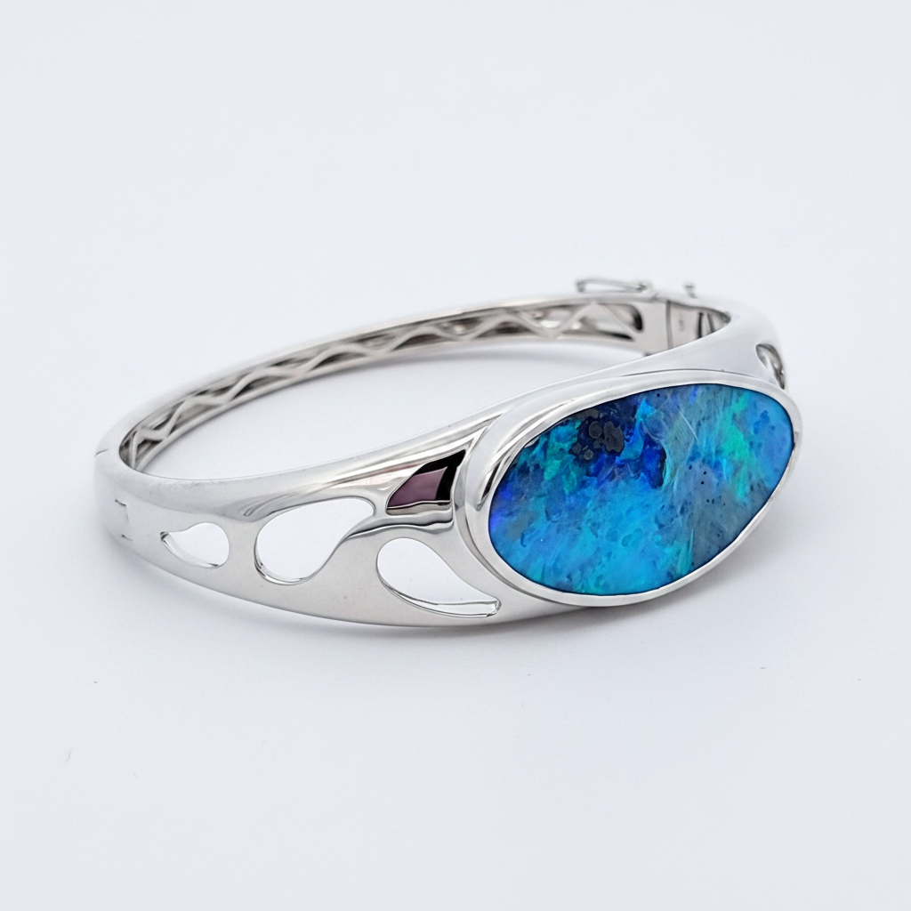 A bangle featuring a solid boulder opal with a combination of blue and green colors, set in a white gold mounting.